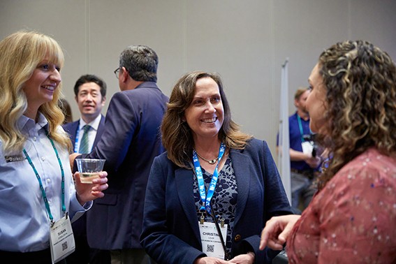 Three women engaged in conversation at a conference, sharing ideas and insights in a professional setting